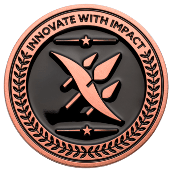 Circular copper challenge coin with black enamel, featuring the text Innovate With Impact, stars, laurel wreath, and a central abstract wing emblem.
