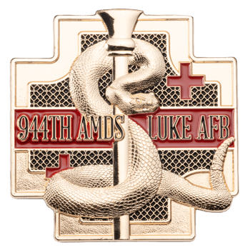 Gold-toned cross-shaped challenge coin featuring a Rod of Asclepius with a coiled snake and the text 944TH AMDS LUKE AFB on a red bar.