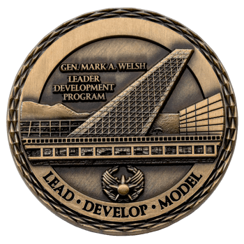Antiqued brass challenge coin featuring the Gen. Mark A. Welsh Leader Development Program text with architectural imagery and a winged star emblem.