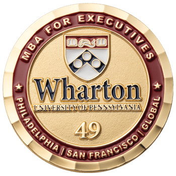 Gold round challenge coin for Wharton MBA for Executives featuring the school crest, the number 49, and red enamel border with campus locations.