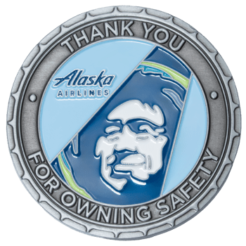 Round silver medallion with blue enamel featuring the Alaska Airlines logo and a stylized portrait face.