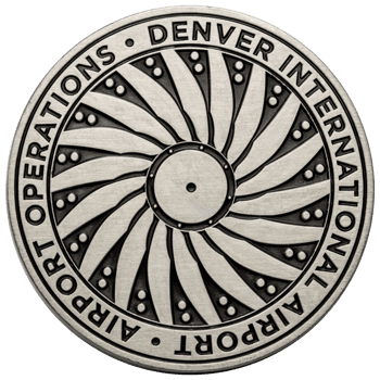 Antiqued silver challenge coin featuring a spiral turbine design and the text Denver International Airport Operations.