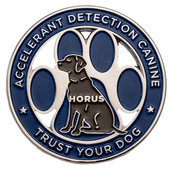 Circular blue and silver enamel challenge coin featuring a black dog silhouette named Horus in front of a paw print cutout.