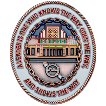 Oval challenge coin featuring the Maumee Indoor Theatre facade, a chain link border, and a leadership quote on a white background.