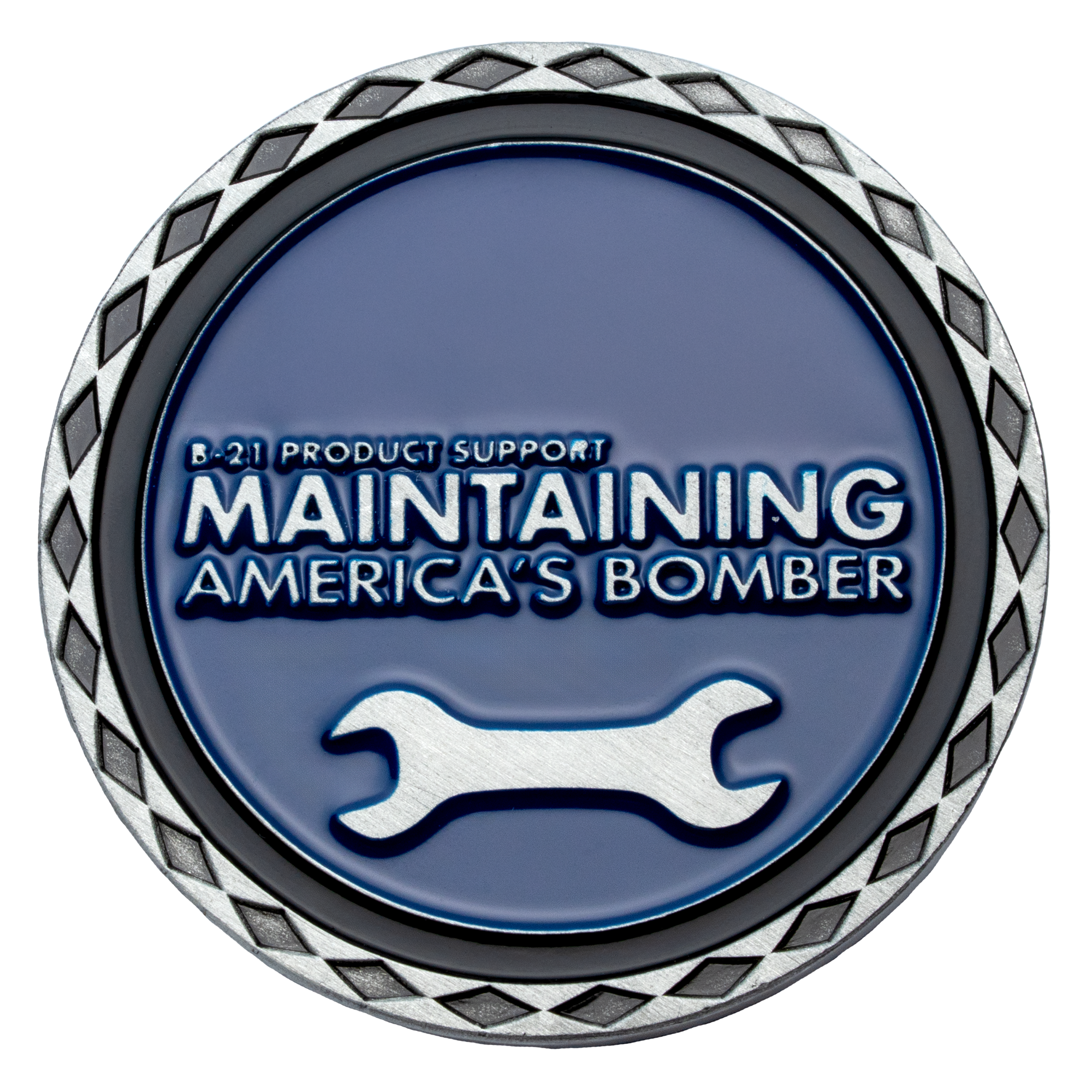 Circular challenge coin with blue enamel, silver wrench icon, and text 'Maintaining America's Bomber' with a diamond pattern border.