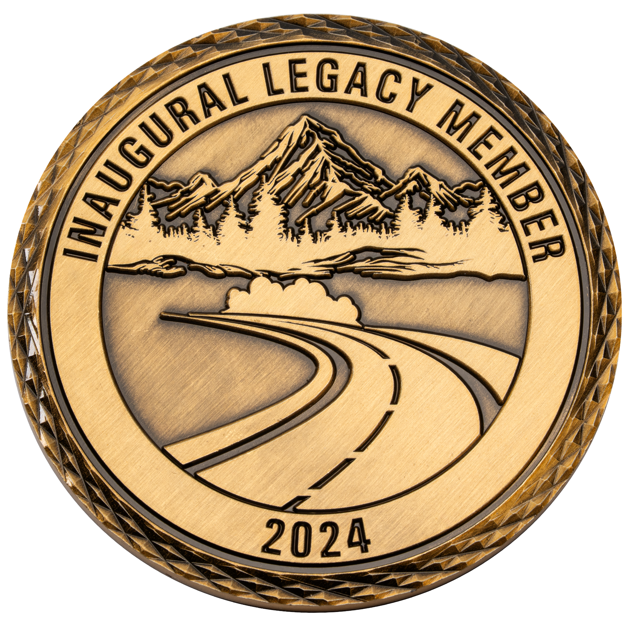 Antiqued gold challenge coin featuring a winding road leading toward mountains and evergreen trees with Inaugural Legacy Member 2024 text.