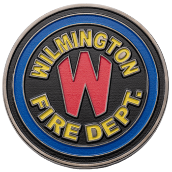 Circular custom medallion with Wilmington Fire Dept. in yellow lettering, a large red W in the center, and a blue outer ring on a black textured background.